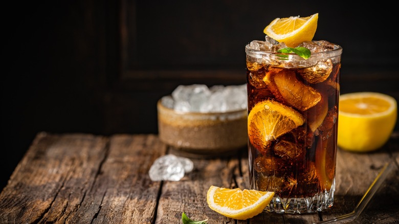 A glass of cola, liquor, and lemon slices