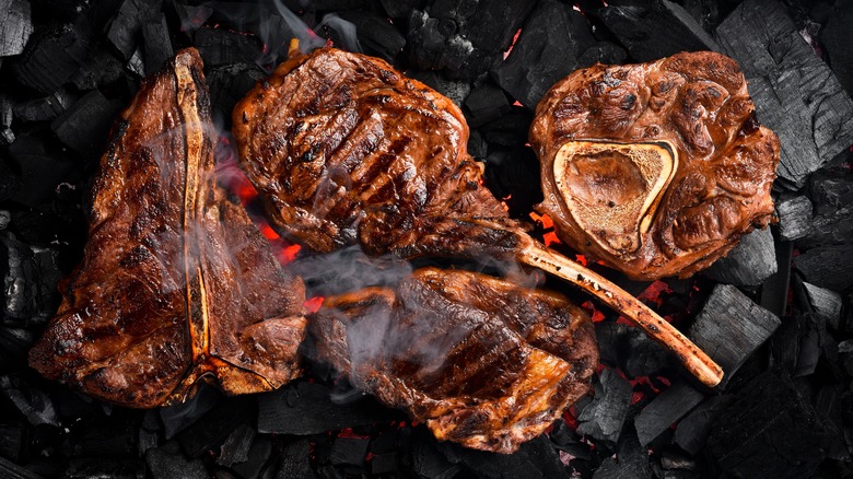 A collection of grilled steaks on top of charcoal.