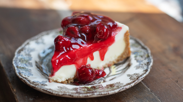 Slice of berry cheesecake with sauce on a plate.