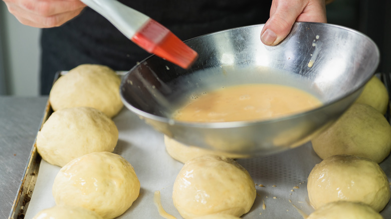 brushing egg wash on rolls