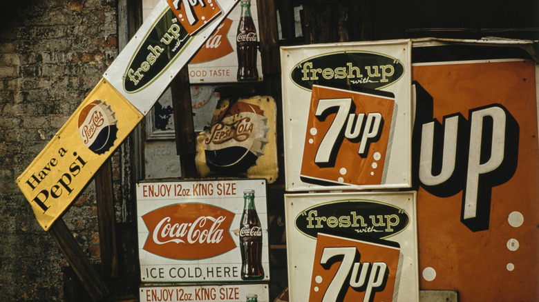Vintage advertising signs for 7 Up, Pepsi, and Coca-Cola, the 7 Up sign featuring the slogan 