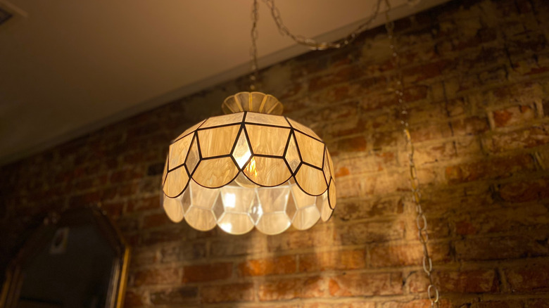 gold-toned Tiffany hanging lamp in front of brick wall