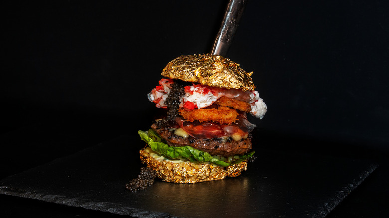 Golden boy wagyu burger, top bun stuck with knife, against dark background