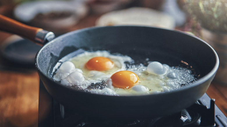 Two sunny side up eggs frying in a skillet