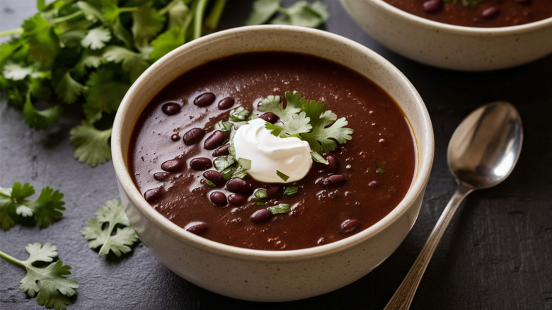 Bowl of black bean soup topped with sour cream and cilantro