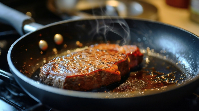 close up of steak searing in pan