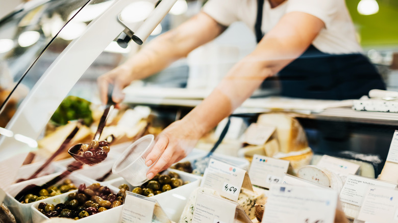 Deli clerk scooping olives