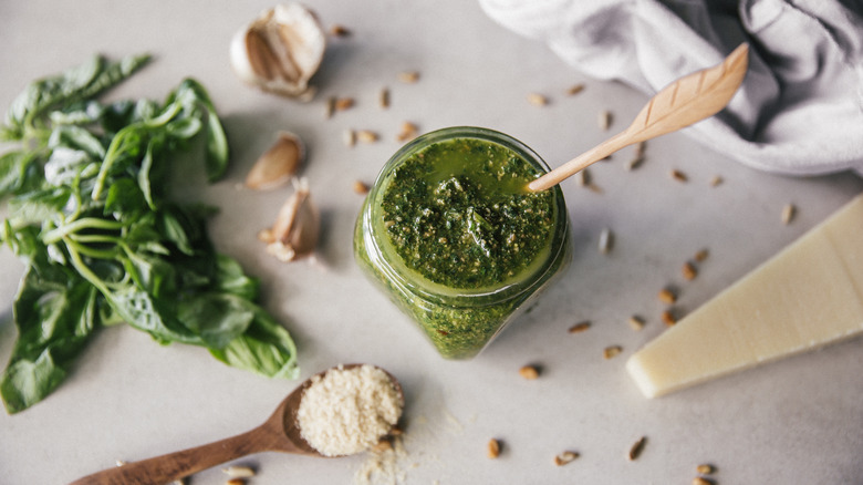 Jar of pesto surrounded by its main ingredients