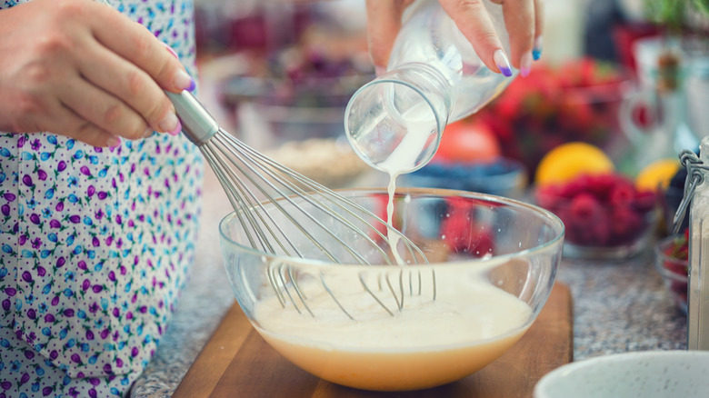 Person adding milk to batter