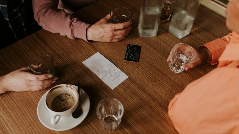 Restaurant guests sitting around a check on the table