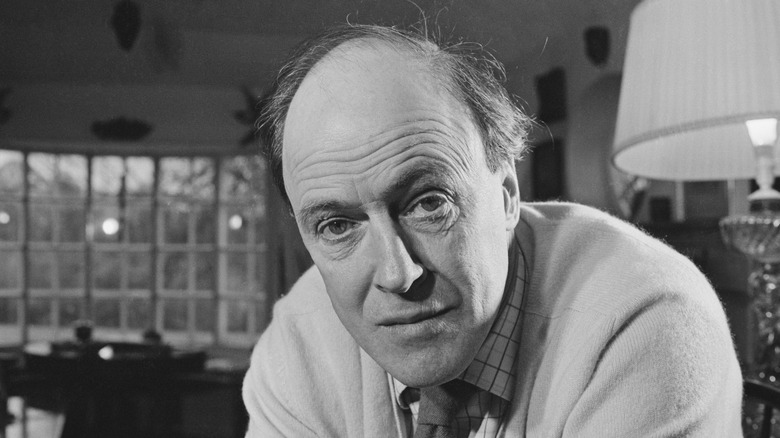 Black-and-white photo of writer Roald Dahl at middle age sitting in a living room