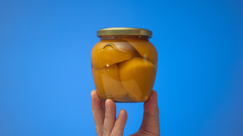 Holding jar of canned peaches
