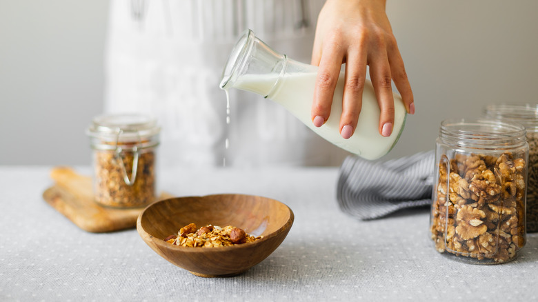 woman pouring milk into a bowl of granola