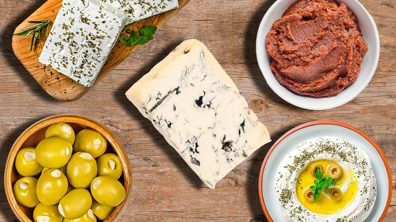 blue cheese, feta, olives, labneh, and miso paste on wooden table