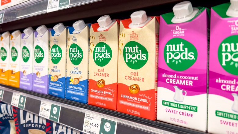 A  row of Nutpods creamers in the refrigerated section of a grocery store, the Almond & Coconut Creamer on the end.