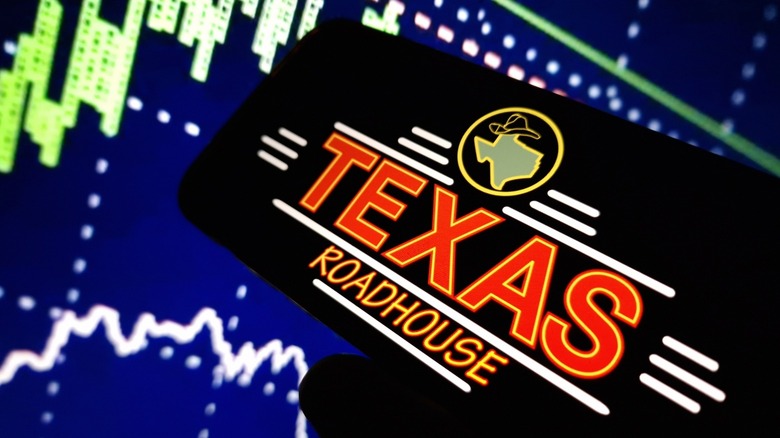 Texas Roadhouse logo on phone with data in background