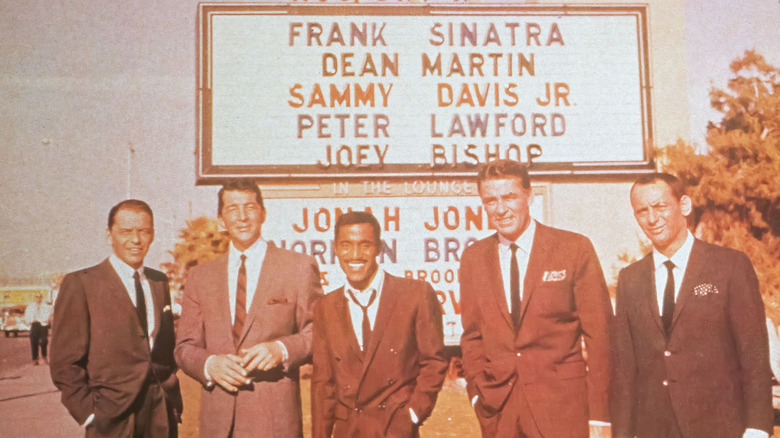 photo of the Rat Pack smiling and standing in front of billboard