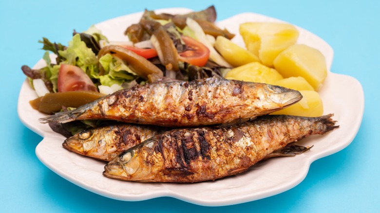 Sardines, potatoes, and salad on plate