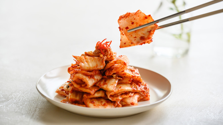 Person picking up cabbage kimchi with chopsticks