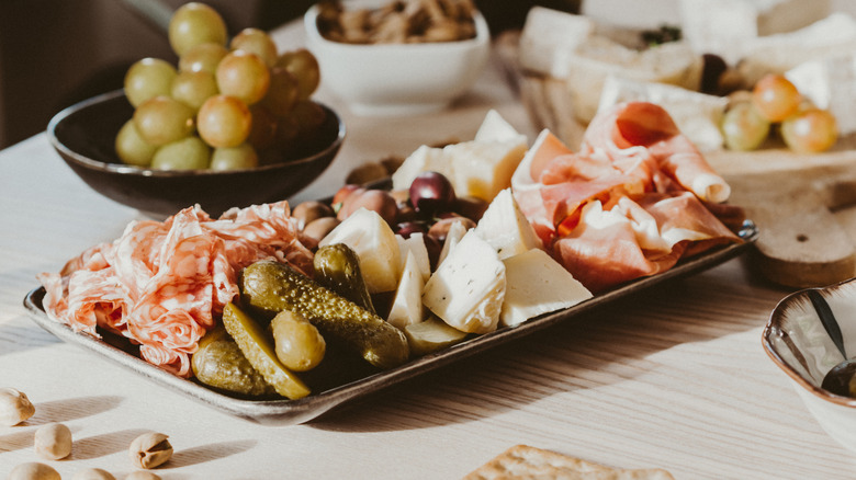 Charcuterie platter with meat, cheese, pickles, and grapes