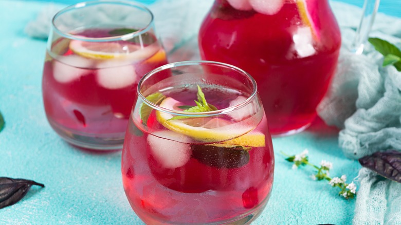 Two glasses of blackberry lemonade with mint and lime slices