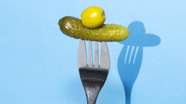 an olive and a pickle on a fork