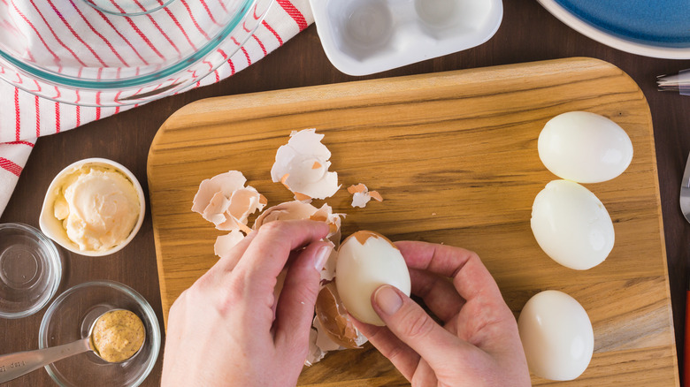 hands peeling boiled eggs