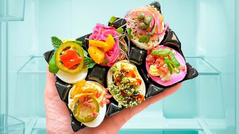 a platter of colorful deviled eggs with toppings