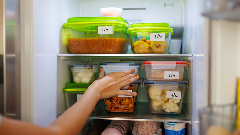 hand reaching for leftovers in plastic containers