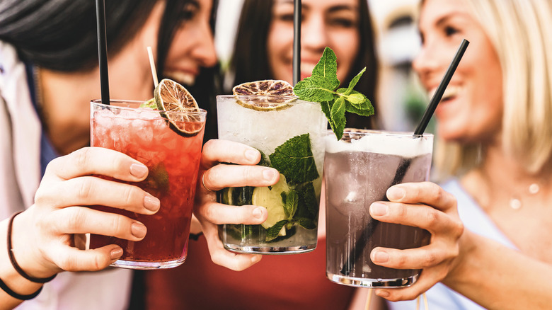 Three women holding mixed drinks