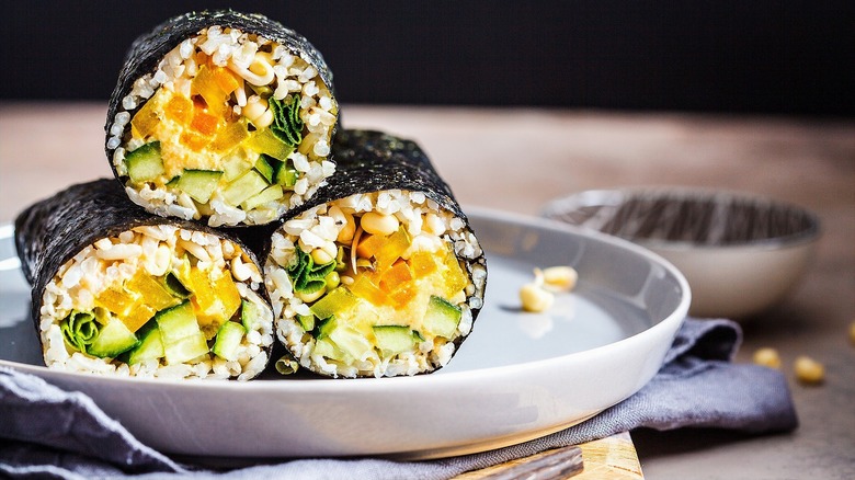 Halved vegan sushi burritos on grey plate