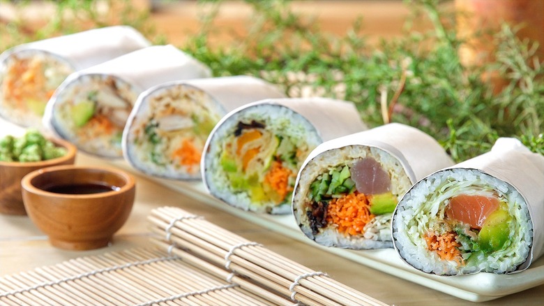 Row of halved sushi burritos wrapped in butcher paper