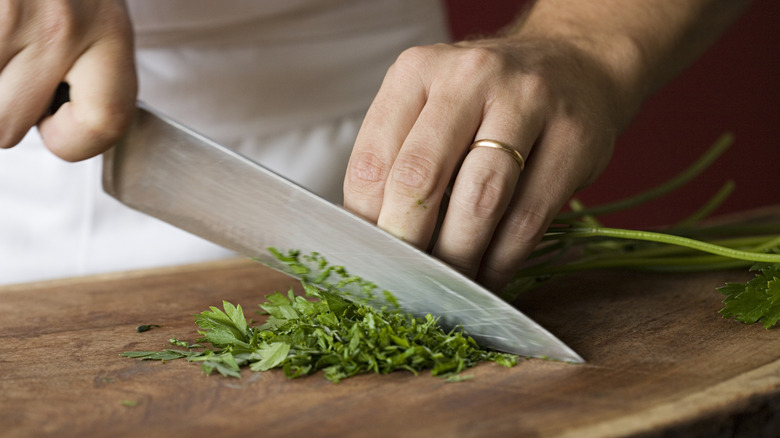 person chopping fresh herbs with a knife