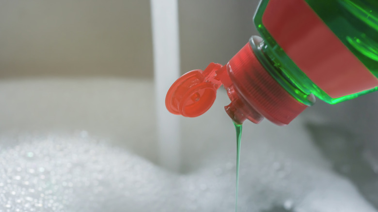 Dish soap pouring into sink filled with bubbles