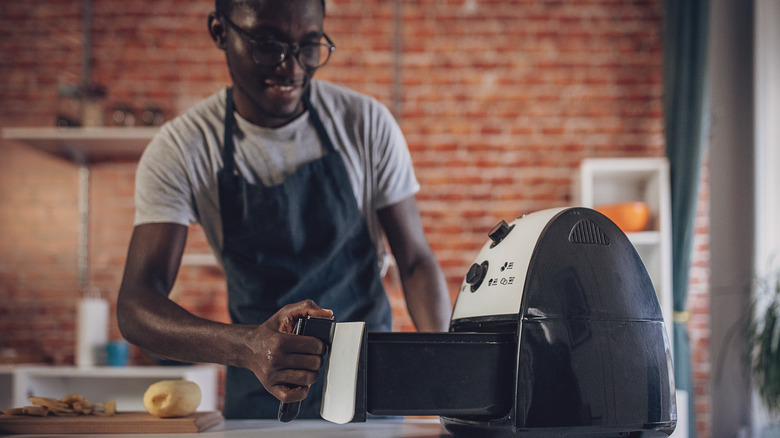 Man looking at open drawer of air fryer