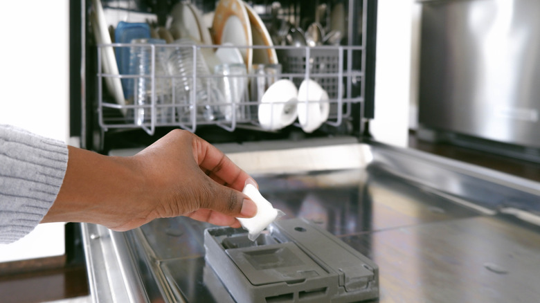 Hand putting dishwashing pod into dishwasher