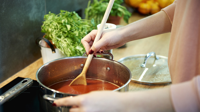 stirring a pot of tomato soup on stovetop