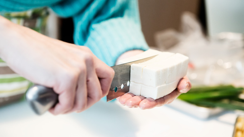 person slicing block of tofu