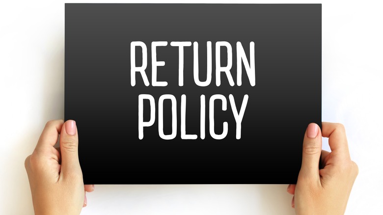 woman holding "return policy" sign