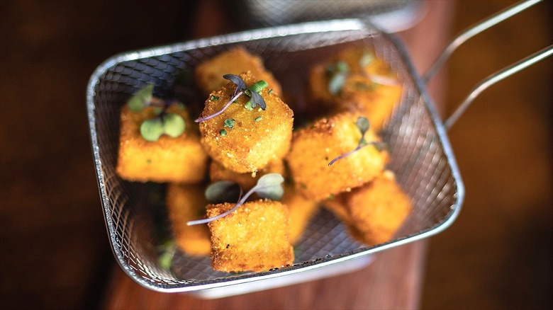 Polenta croutons in a handheld wire strainer