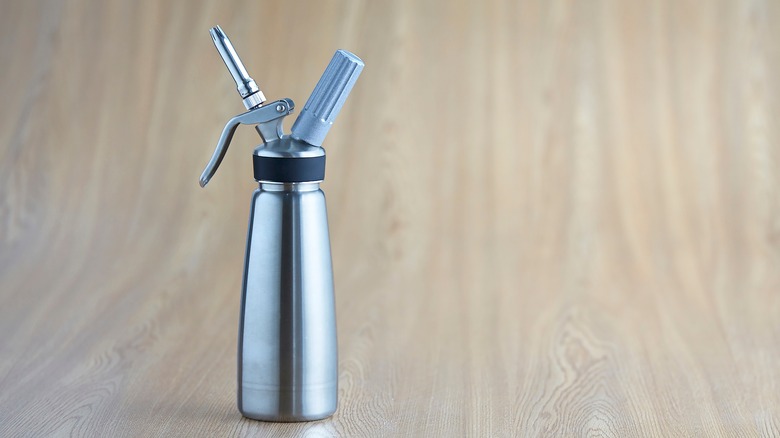 whipped cream dispenser against wood background