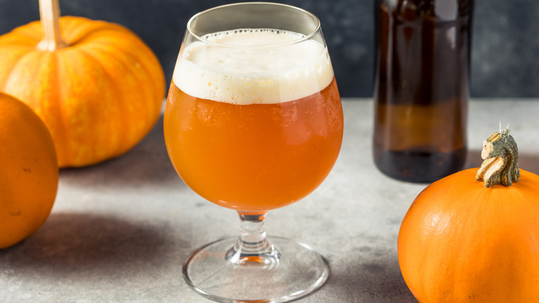 glass of pumpkin beer with pumpkins