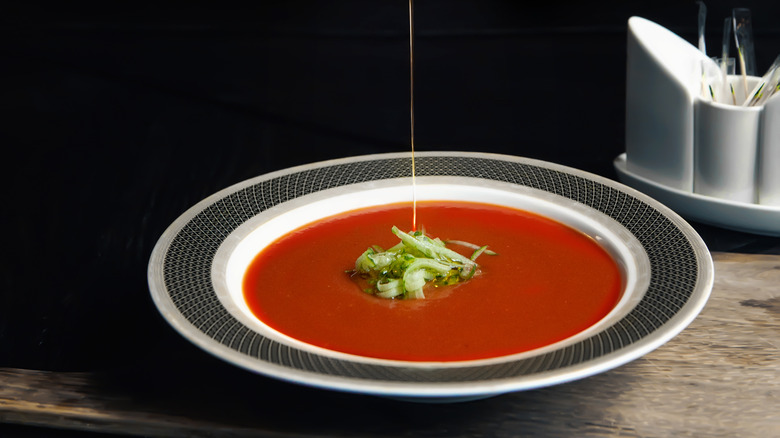 oil being drizzled on a bowl of tomato soup