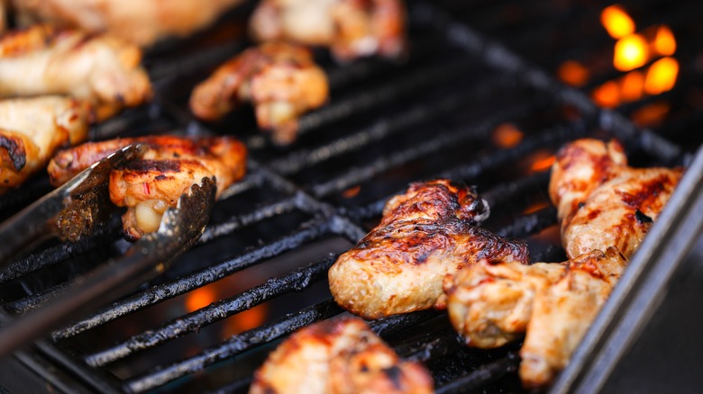 Chicken wings cooking on grill.