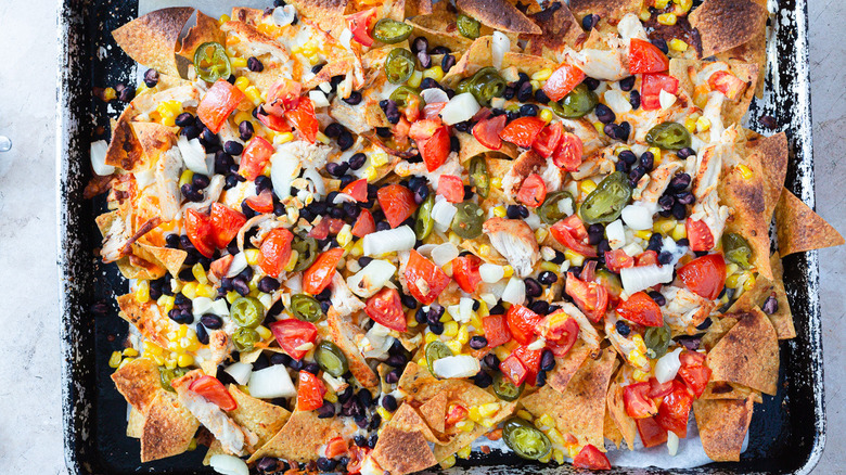 Nachos with toppings in baking sheet