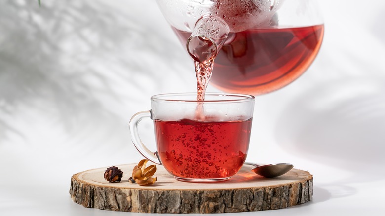 hot tea pouring from a glass teapot to a glass cup