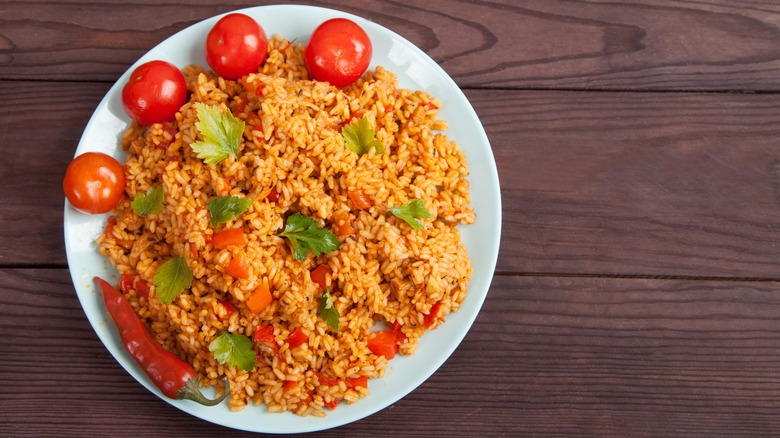 a plate of jollof rice with tomatoes and chili pepper