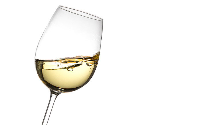 a glass of white wine on white background