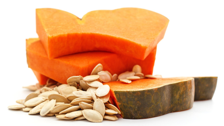 Sliced pumpkin pieces with seeds are on a white background.