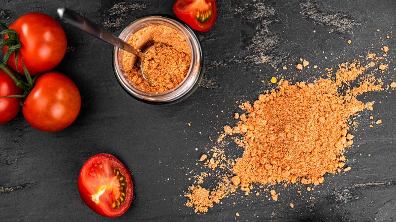 Tomato powder in jar with tomatoes on the side